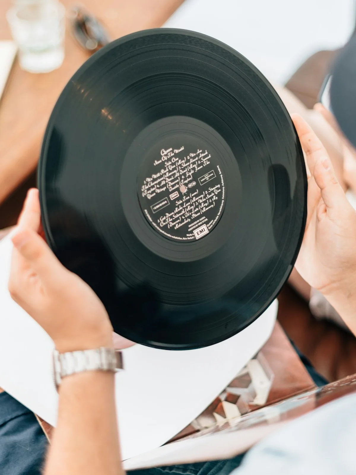 A collector holding a vinyl record with both hands by its edges to examine the label and surface